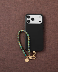Phone with turquoise stone strap on styled background by STICKYZOO