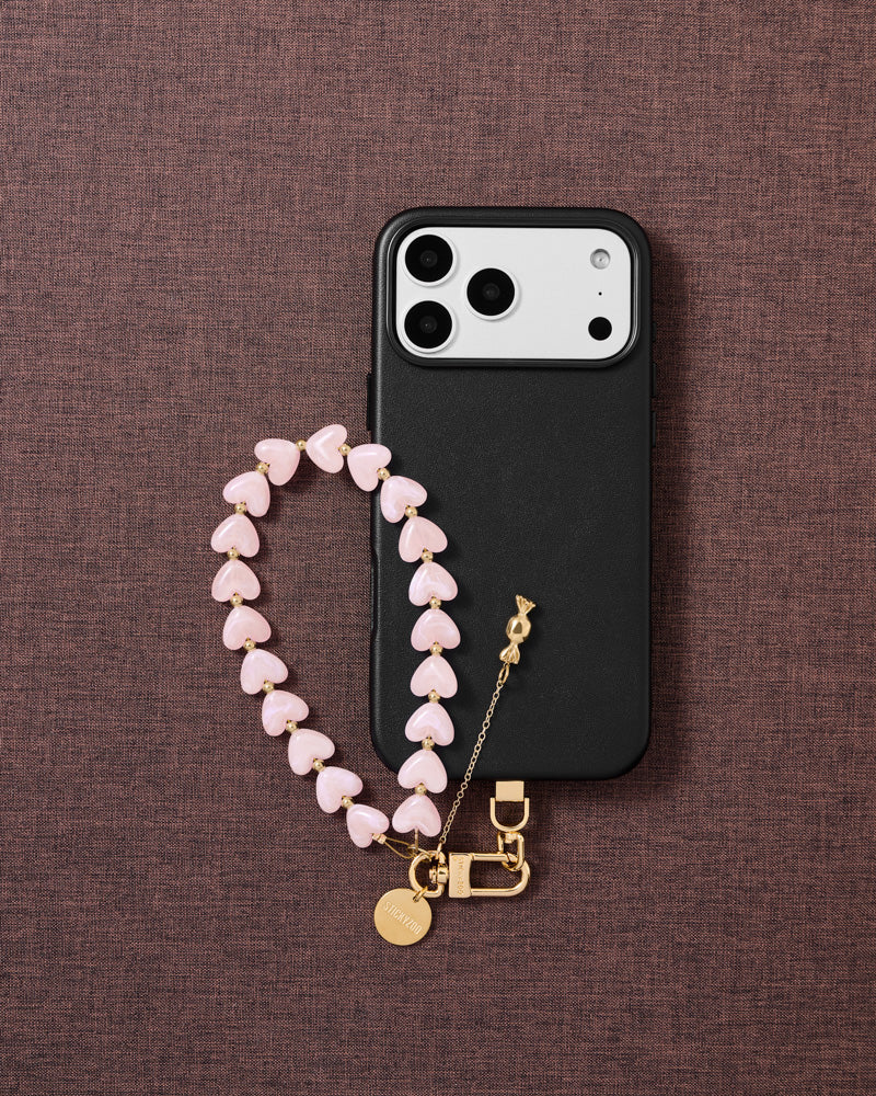 Flat-lay of blush candy phone strap with engraved gold hardware and Phone Strap Card