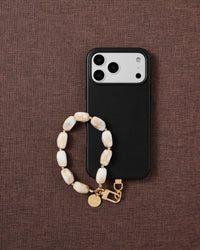 Phone with ivory marble strap on brown fabric lifestyle flat-lay