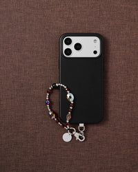 Crimson faceted glass bead phone strap styled with phone on brown fabric flat-lay