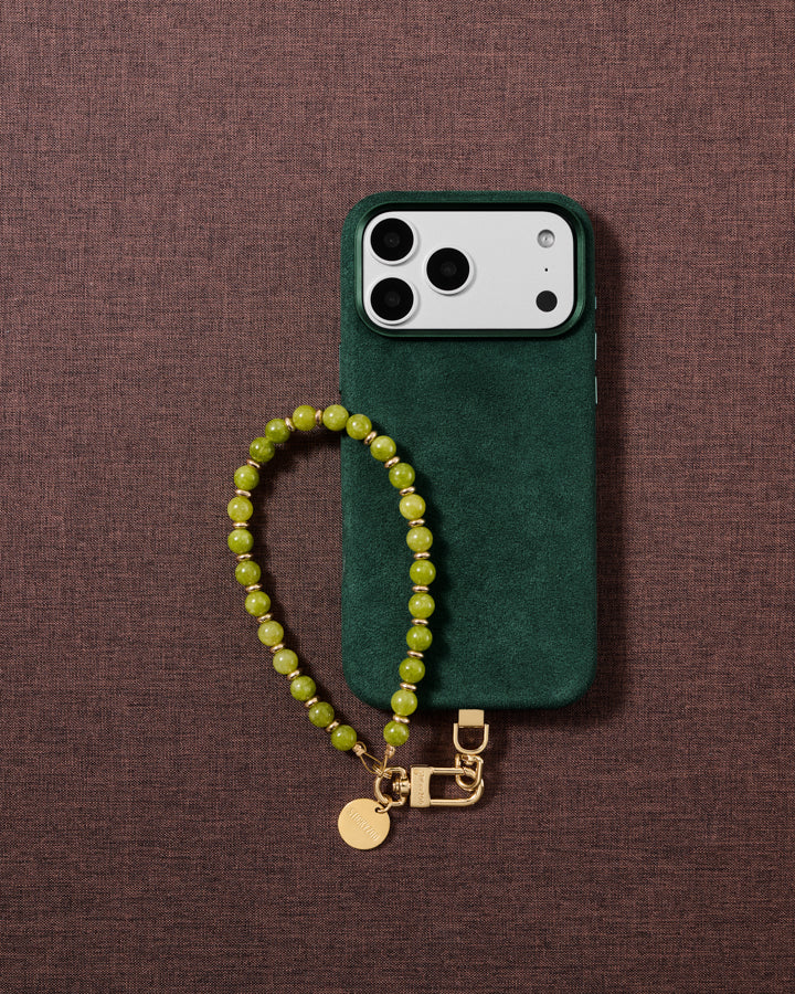 Handmade olive-green stone bead wrist strap styled in a lifestyle flat-lay on fabric