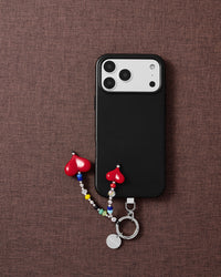 Double red heart phone charm styled with phone on brown fabric flat-lay