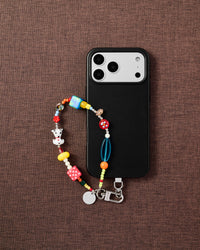 Dalmatian dice phone strap styled with phone on brown fabric flat-lay