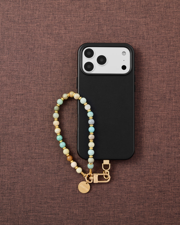 {{Designed in Amsterdam}} Amazonite stone bead phone strap styled with phone on brown fabric flat-lay