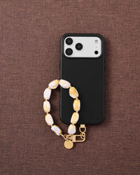 Amber marble phone strap with black phone case on dark fabric lifestyle flat-lay