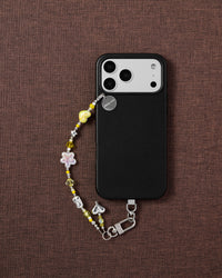 Phone with yellow charm bead strap on styled fabric background by STICKYZOO