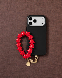 STICKYZOO crimson star phone strap on warm flat-lay — Designed in Amsterdam