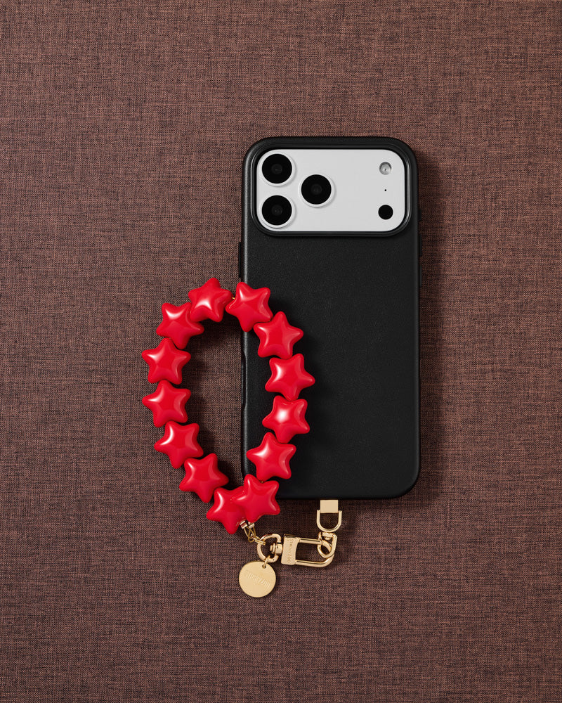 STICKYZOO crimson star phone strap on warm flat-lay — Designed in Amsterdam