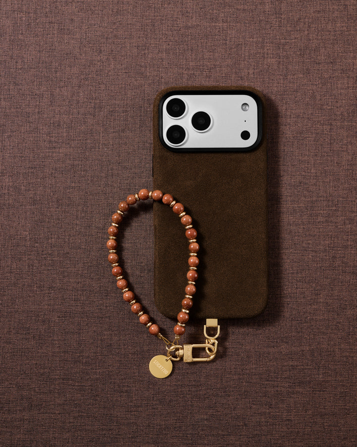 Handmade copper goldstone wrist strap styled in a lifestyle flat-lay on soft fabric