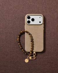 Handmade bronze stone wrist strap styled on fabric, golden banded beads in a lifestyle flat-lay