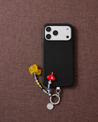 Tangerine duck heart phone strap with black phone case on dark fabric lifestyle flat-lay