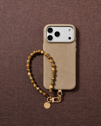 Flat-lay of the handmade tan and brown stone bead phone strap styled on soft neutral fabric.