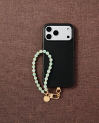 Phone with Mint Bead strap on brown fabric lifestyle flat-lay