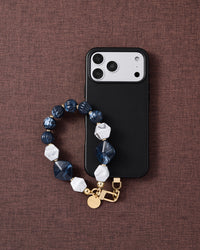 Sapphire marble cluster phone strap with black phone case on dark fabric lifestyle flat-lay