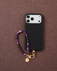 Phone with Midnight Aura strap on brown fabric lifestyle flat-lay