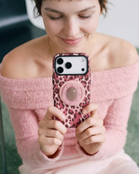 Rose leopard phone case held in one hand with the retractable MagSafe pop-grip extended on the back