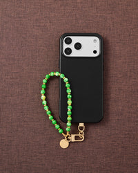 Phone with Jade Speckle Orbit strap on brown fabric lifestyle flat-lay