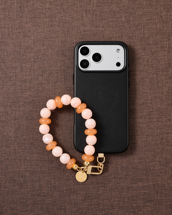 Peach pearl bead phone strap styled on fabric, loved by thousands of STICKYZOO customers