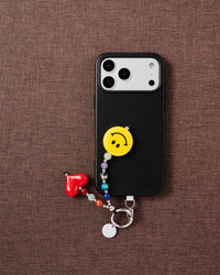 Smiley heart phone strap flat-lay on dark brown fabric by STICKYZOO