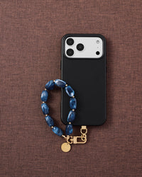 Phone with indigo marble strap on brown fabric lifestyle flat-lay