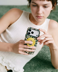 Jade leopard phone case held in two hands while the retractable grip props the phone for tapping the screen.