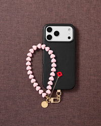 Flat-lay of bubblegum kiss phone strap with engraved gold hardware and Phone Strap Card