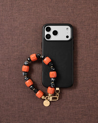 Ember-orange and black bead phone strap styled on fabric, loved by thousands of STICKYZOO customers