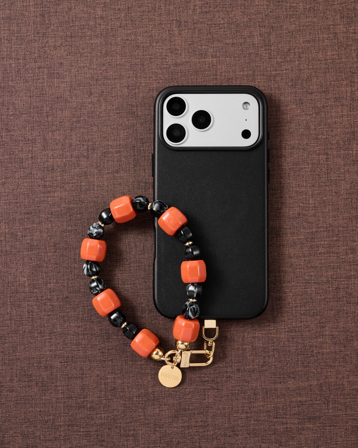 Ember-orange and black bead phone strap styled on fabric, loved by thousands of STICKYZOO customers