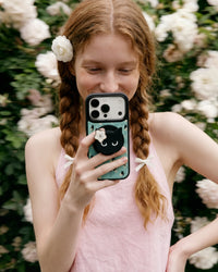 Midnight cat phone case held up with the cat-face grip popped out and the mint floral case on show