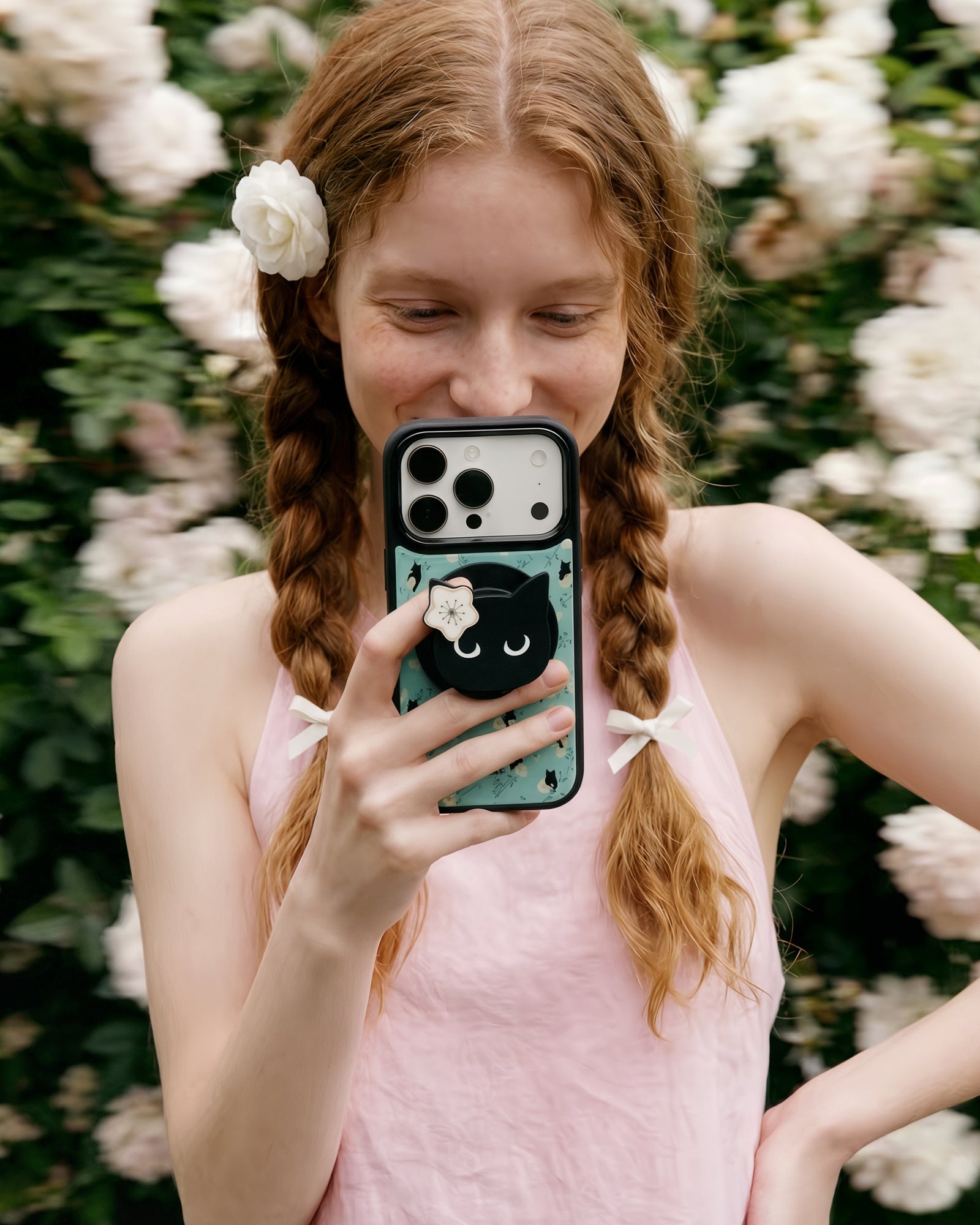 Midnight cat phone case held up with the cat-face grip popped out and the mint floral case on show