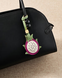 Pitaya leather bag charm styled on a black leather handbag showing layered French Alran skin, flesh, and green sepal detail