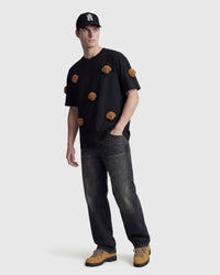 Model wearing STICKYZOO black Poodle Parade T-Shirt with hand in pocket showing plush poodles