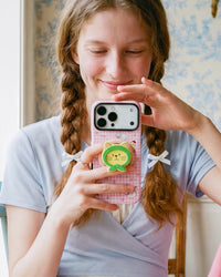Fingers gripping the retractable MagSafe pop-grip on the back of the pink green-hood cat phone case.