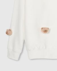Close-up of plush bear faces near lower hem and sleeve cuff showing ribbed trim