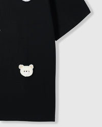 Close-up of single plush bear face with checkered ears near hem on black cotton