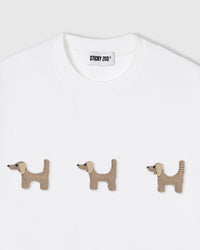Close-up of houndstooth plush dachshund on white cotton showing checked pattern and dimension