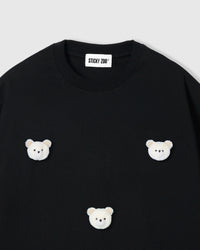 Close-up of plush bear face with gingham checkered ears on black cotton