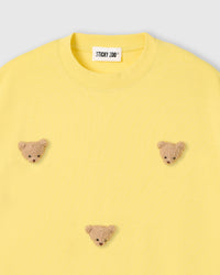 Close-up of plush bear face appliques on lemon 230gsm cotton showing fuzzy 3D texture and embroidered features