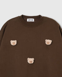 Close-up of plush teddy bear face with check ears on dark brown cotton showing warm tonal contrast