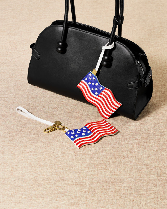 {{Designed in Amsterdam}} USA flag charm draped on black bag in studio lighting — handmade French Alran leather by STICKYZOO