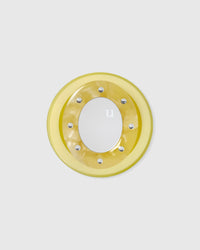 Close-up of the glossy yellow acrylic-resin grip medallion with a studded ring and a round mirror set inside.