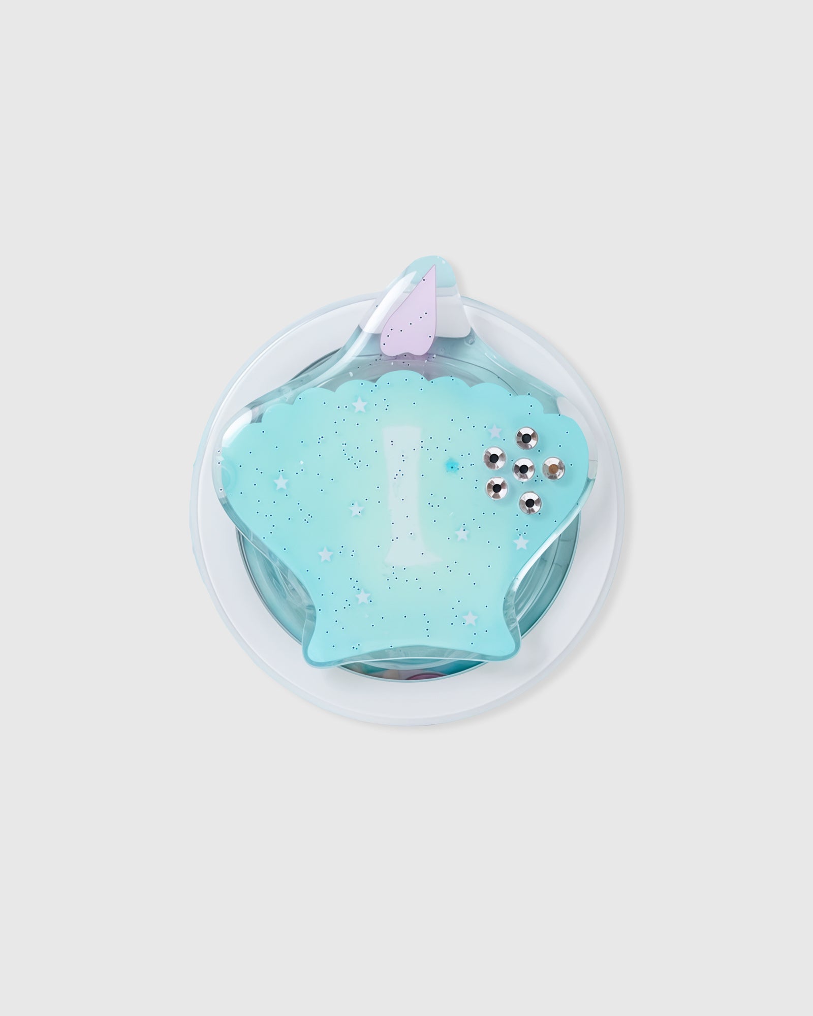 Close-up of the 3D teal seashell with stars and crystal studs embedded inside the acrylic-resin grip top