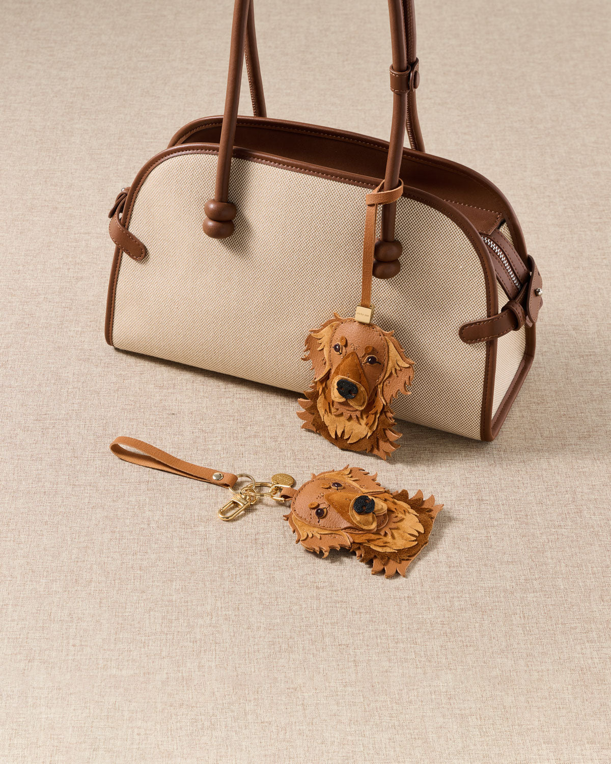 {{Bag strap or keychain.}} both editions styled with bag — strap loop attached, keychain clip on linen. French Alran goatskin, 72 hours by hand.