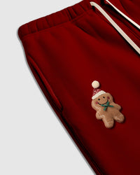 Detail shot of hand-stitched gingerbread character on red STICKYZOO sweatpant showing icing-stitch lines