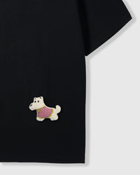 Detail of plush scottie dog applique on lower body area of black tee showing patterned vest