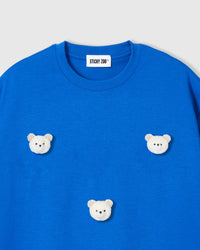 Close-up of white plush bear with gingham ears on royal blue cotton