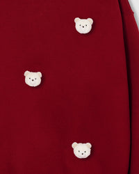 Multiple plush bear faces showing dimensional white texture against rich red fabric