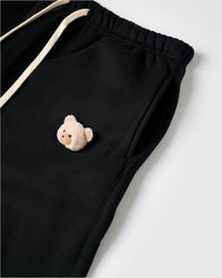 Detail of plush bear face with checkered ears on STICKYZOO black sweatpant showing handmade texture