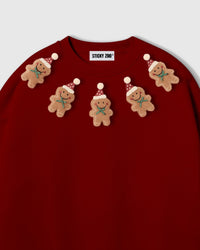 Close-up of hand-stitched gingerbread arc on red sweatshirt showing Santa hats and icing detail