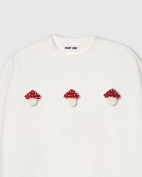 Close-up of plush mushroom applique with red polka-dot cap and cream stem on cream cotton